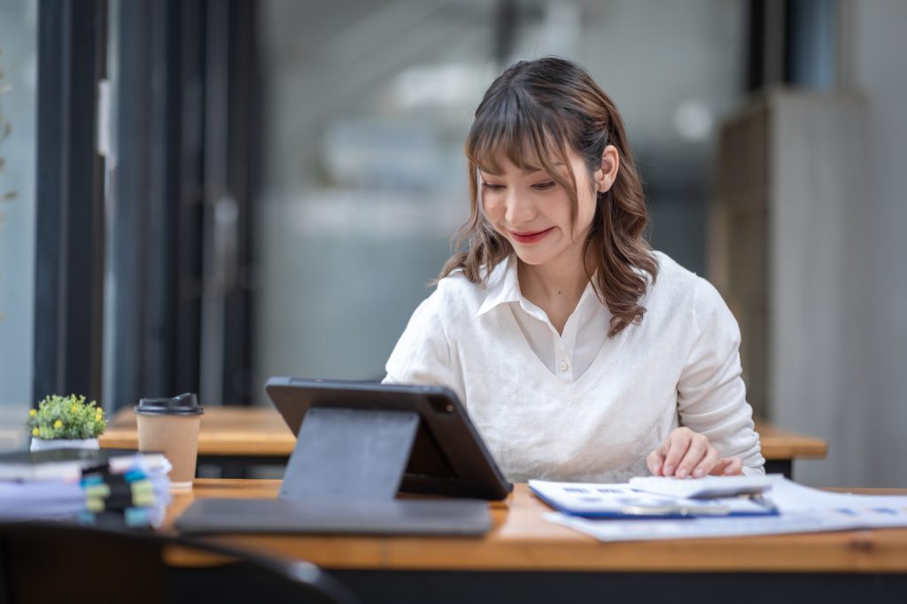Asian Business woman using calculator and laptop for doing math finance on an office desk, tax, repo